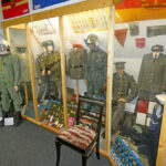 Bundeswehr-themed exhibition showing soldier uniforms, equipment, and a military workspace in a museum display