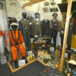 Ausstellung zur Bundeswehr mit Soldatenuniformen, Ausrüstung und militärischem Arbeitsbereich in einer Museumsvitrine